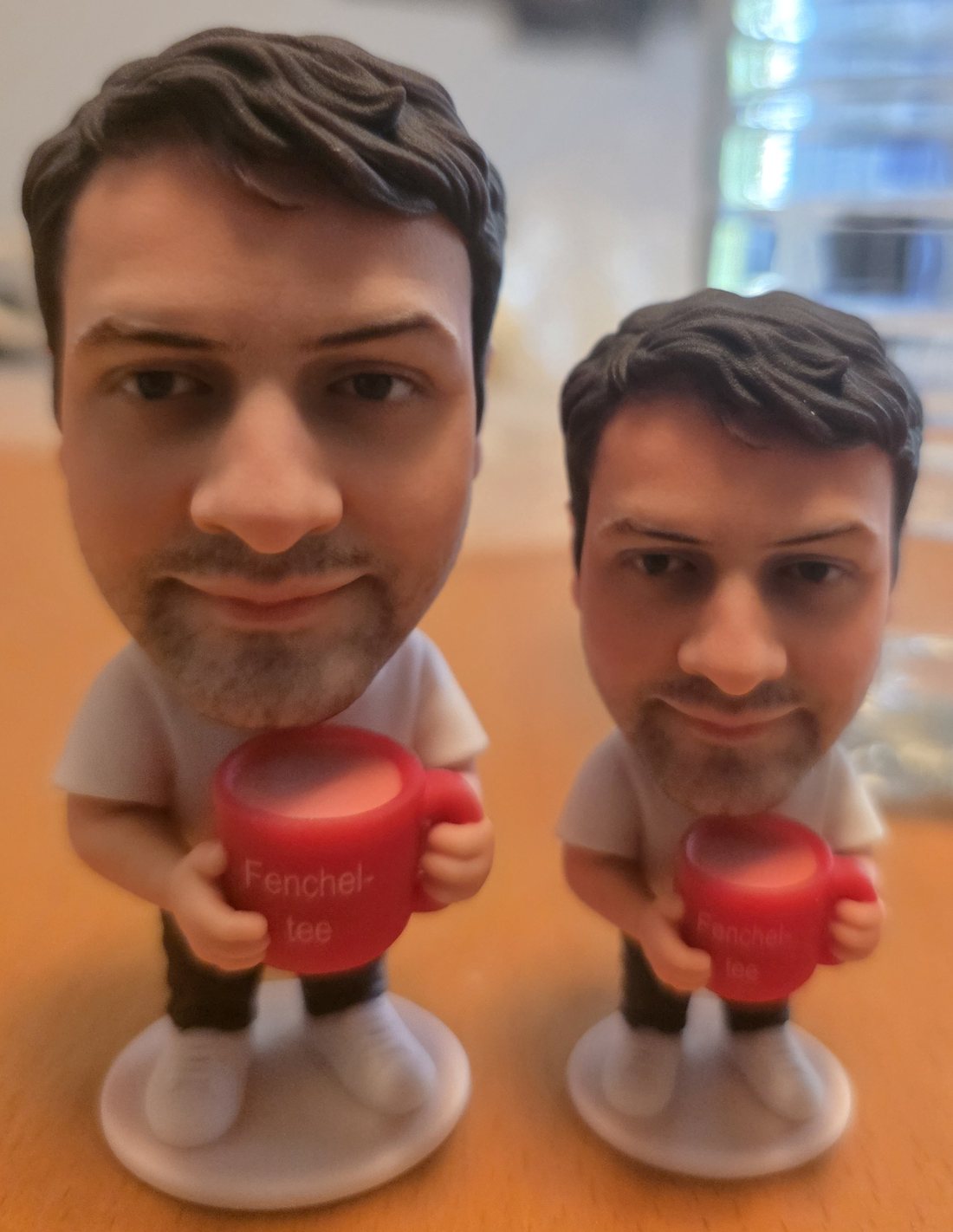 Zwei gedruckte Figuren desselben Mannes mit roter Fencheltee-Tasse, links 10 cm, rechts 8 cm hoch