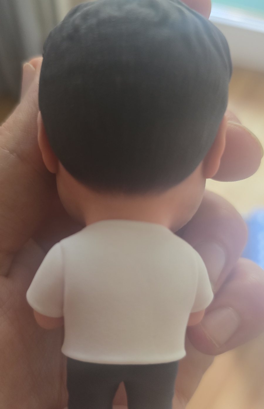 Figur von hinten in der Hand, weißes Shirt und dunkle Hose