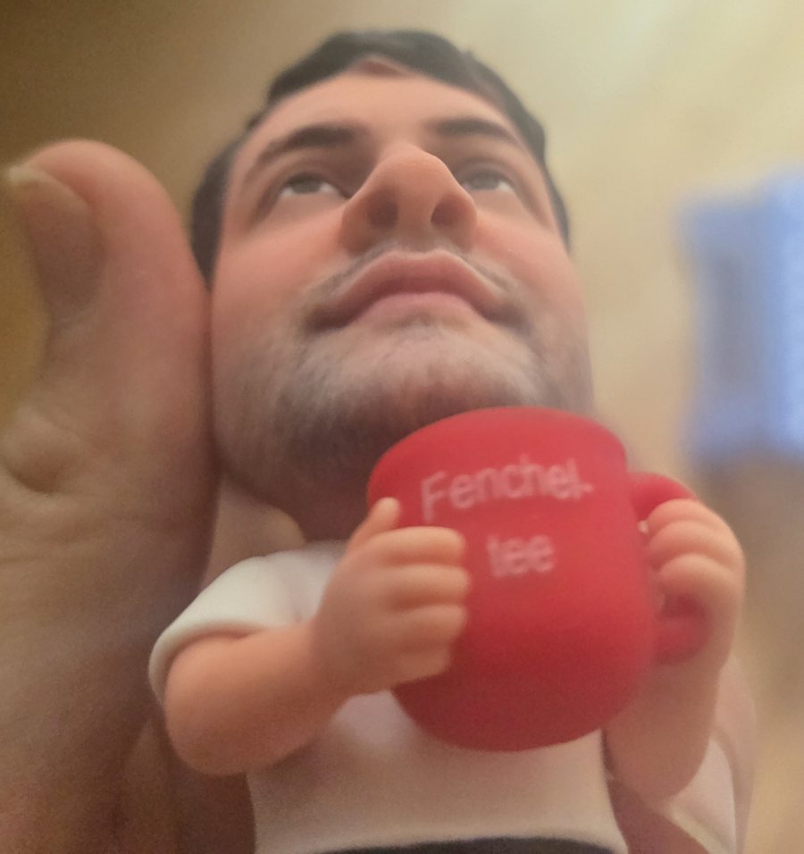 Figur von unten, Hände halten eine rote Tasse mit der Aufschrift Fencheltee